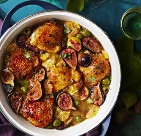 Ein Gericht mit gebratenem Hühnchen, frischen Feigen, Zitronenscheiben und grünen Oliven in einer weißen Schüssel.